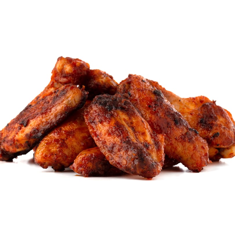 A pile of crispy, saucy chicken wings from Pizza Heaven, isolated on a white background.