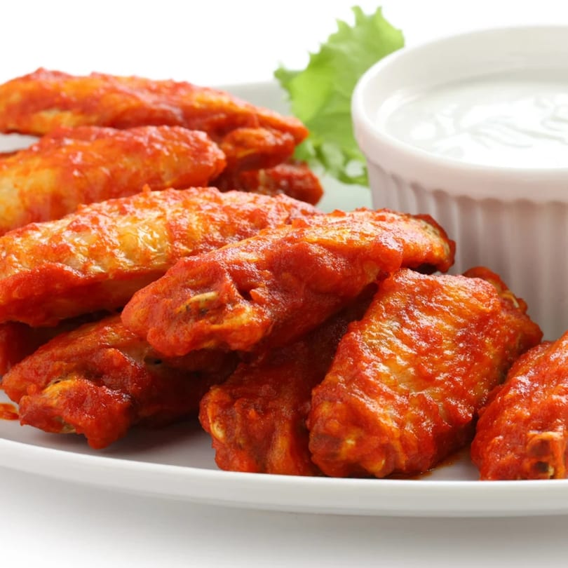 A plate of Pizza Heaven's buffalo wings with a side of ranch dressing and lettuce.
